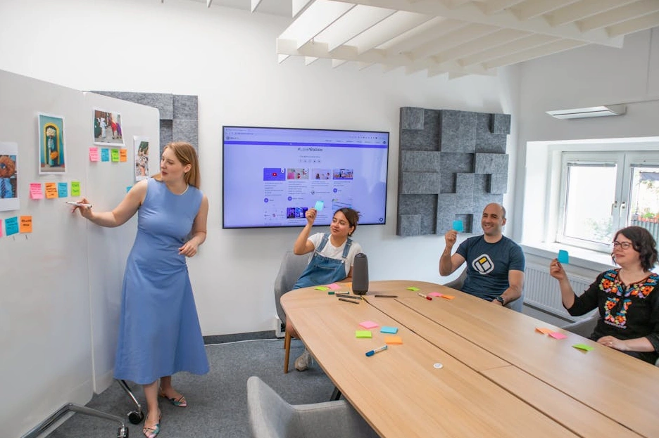 Un team di professionisti che collabora sorridendo davanti a una lavagna.